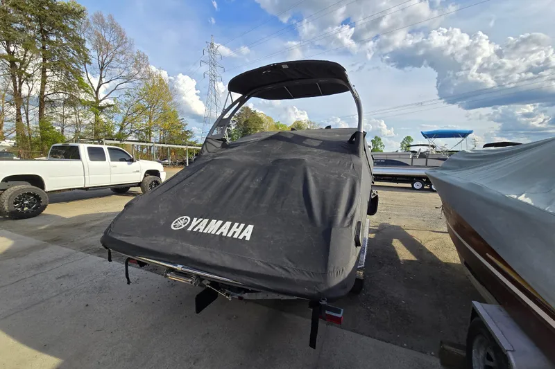 Slide: The Image of 2022 Yamaha Boats 212S covered, parked outdoors with a truck nearby. - 11