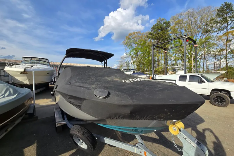 Slide: The Image of 2022 Yamaha Boats 212S covered on trailer, parked outdoors under blue sky. - 12