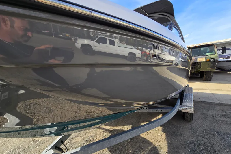 Slide: The Image of 2022 Yamaha Boats 212S on trailer, reflecting nearby vehicles and surroundings. - 2