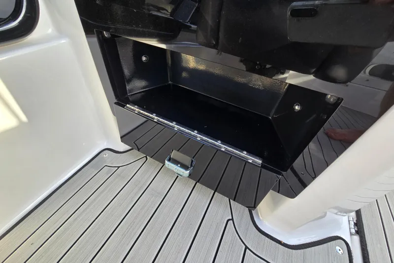 Slide: The Image of Open storage compartment on 2022 Yamaha Boats 212S, featuring sleek black interior and deck flooring. - 27