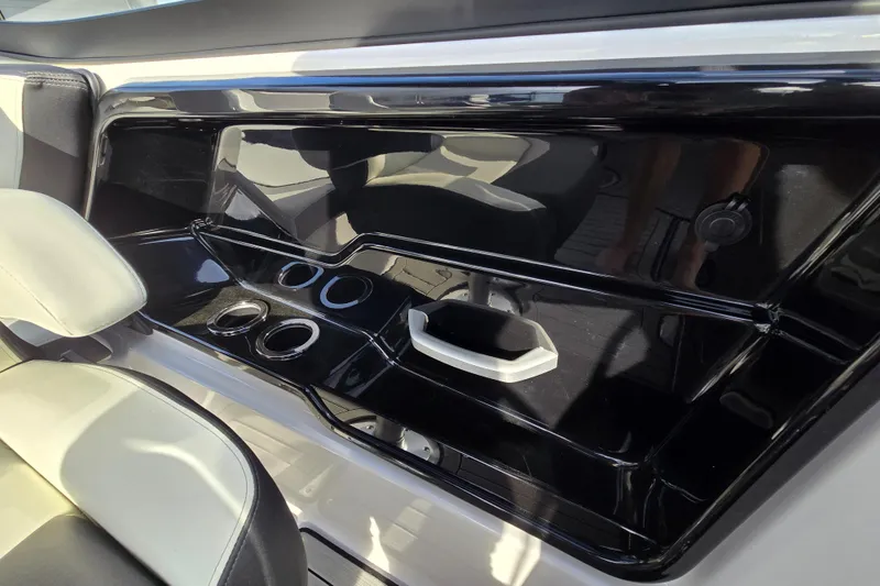 Slide: The Image of Interior of 2022 Yamaha Boats 212S, featuring sleek black console with cup holders. - 29