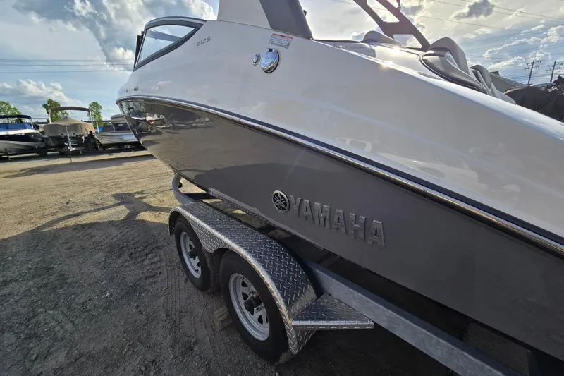 Slide: The Image of 2022 Yamaha Boats 212S on trailer under cloudy sky. - 6