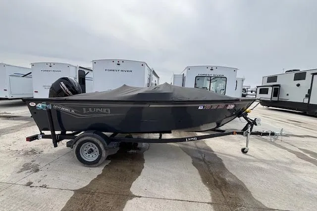 The Image of 2024 Lund 1650 Rebel XL Sport boat on trailer, covered, parked near RVs. - 1