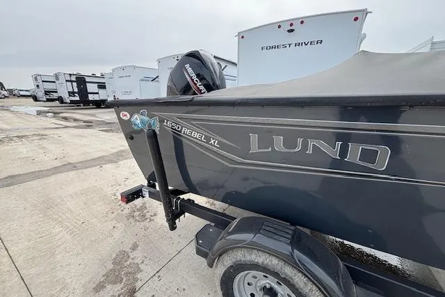 Slide: The Image of 2024 Lund 1650 Rebel XL Sport boat on trailer, parked near RVs. - 2