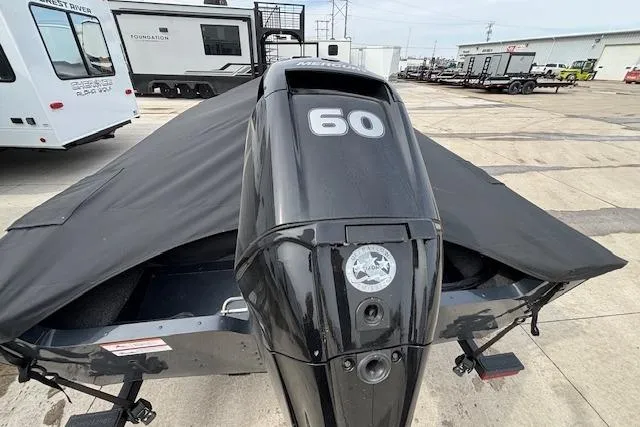 Slide: The Image of 2024 Lund 1650 Rebel XL Sport boat with 60 HP engine, covered and parked outdoors. - 6