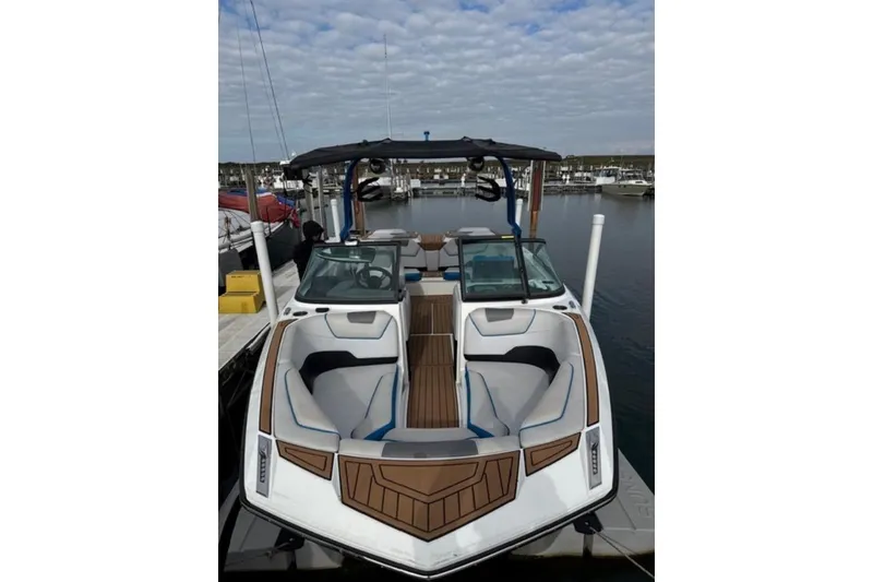 Slide: The Image of 2018 Nautique Super Air Nautique GS22 boat docked at marina under cloudy sky. - 4