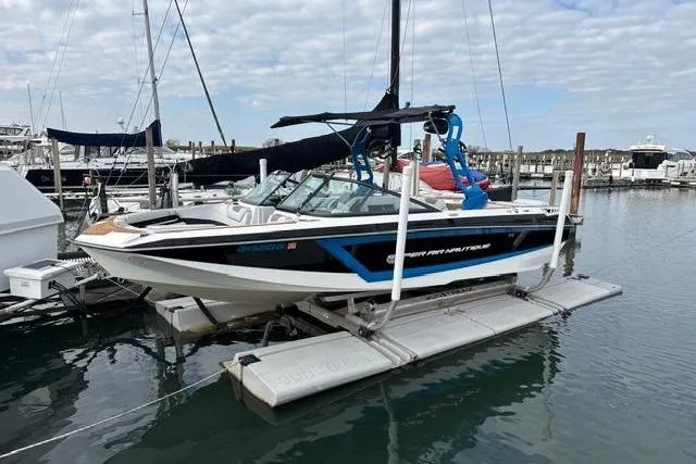 Slide: The Image of 2018 Nautique Super Air Nautique GS22 boat docked at marina with clear sky. - 6