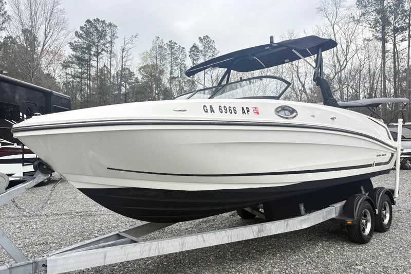 The Image of 2022 Bayliner VR6 Bowrider OB on trailer, parked outdoors with trees in background. - 1