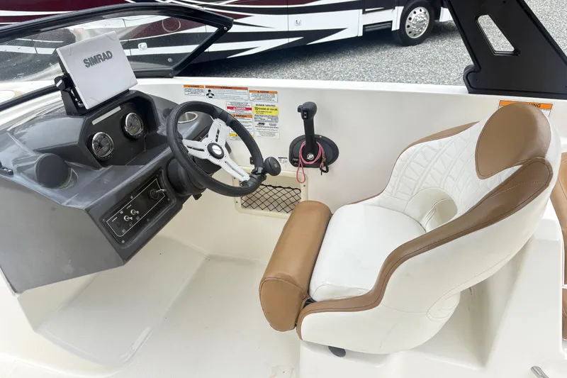 Slide: The Image of 2022 Bayliner VR6 Bowrider OB cockpit with steering wheel, Simrad display, and cushioned seat. - 11