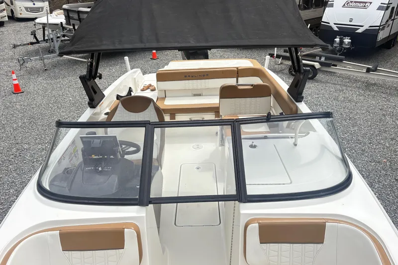 Slide: The Image of 2022 Bayliner VR6 Bowrider OB with black canopy and tan seating, parked on gravel. - 17