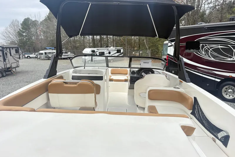 Slide: The Image of 2022 Bayliner VR6 Bowrider OB interior with tan and white seating, parked near RVs. - 8