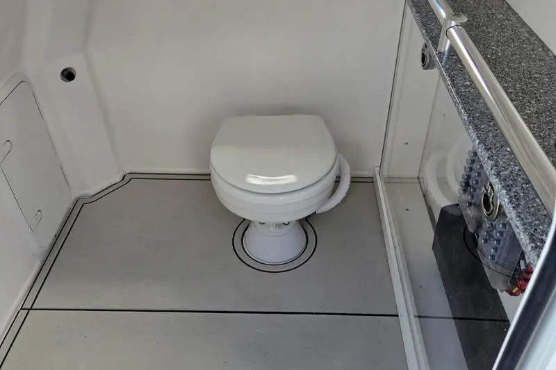 Slide: The Image of Interior of 2026 Twin Vee 280 GFX2 CC boat featuring a compact marine toilet. - 9