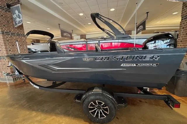 Slide: The Image of 2026 Crestliner 1650 Kodiak Tiller boat displayed indoors on a trailer. - 2