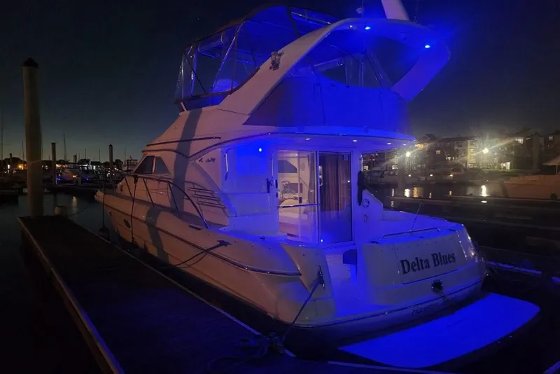 Slide: The Image of 1999 Sea Ray 400 Sedan Bridge yacht illuminated at night in a marina. - 1