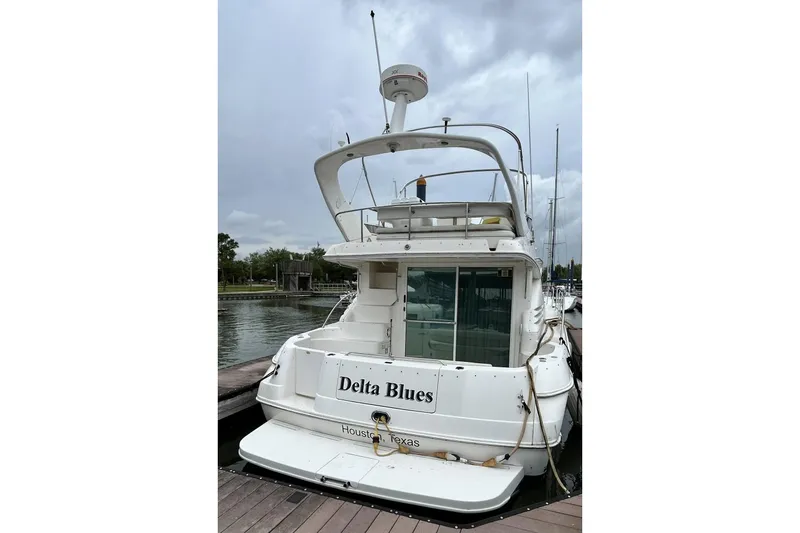 Slide: The Image of 1999 Sea Ray 400 Sedan Bridge yacht docked, rear view with "Delta Blues" name. - 13