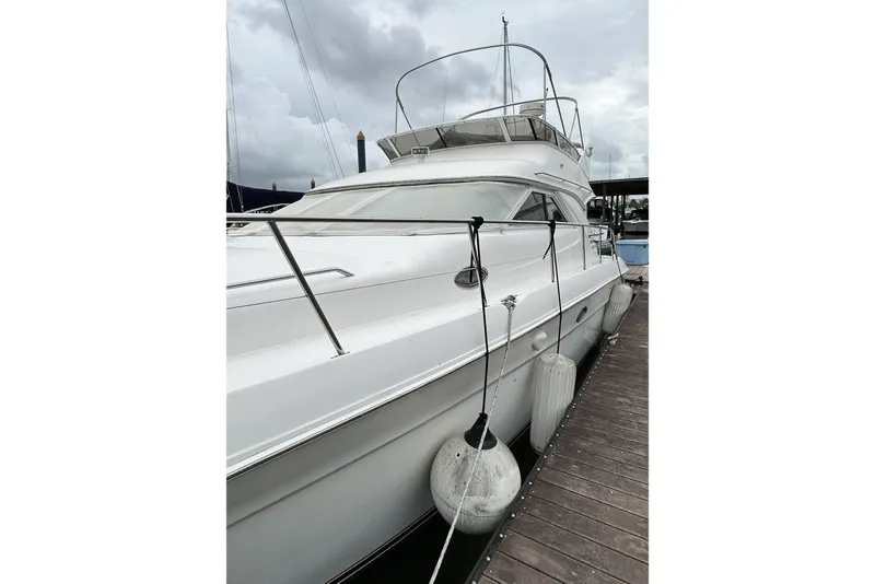 Slide: The Image of 1999 Sea Ray 400 Sedan Bridge yacht docked, showcasing sleek design and white exterior. - 15
