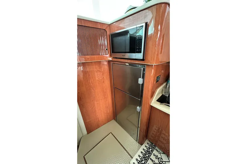 Slide: The Image of 1999 Sea Ray 400 Sedan Bridge kitchen with microwave and stainless steel fridge. - 31