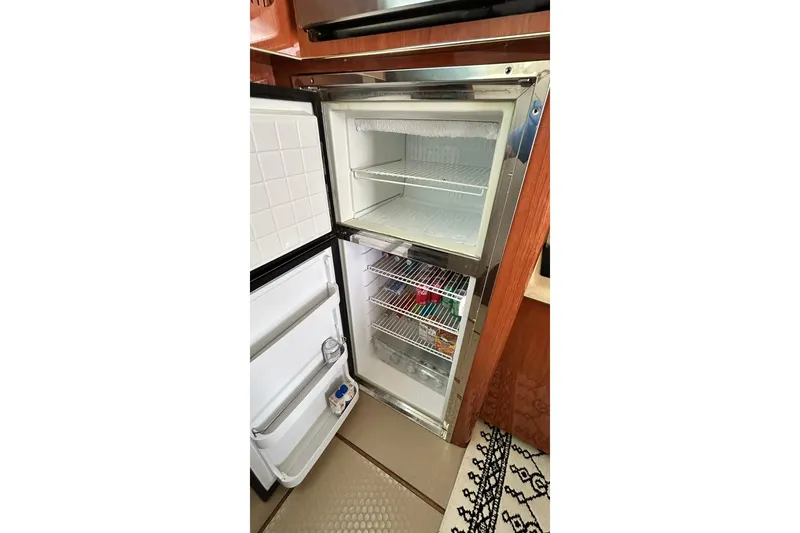 Slide: The Image of 1999 Sea Ray 400 Sedan Bridge refrigerator interior with shelves and door storage. - 32