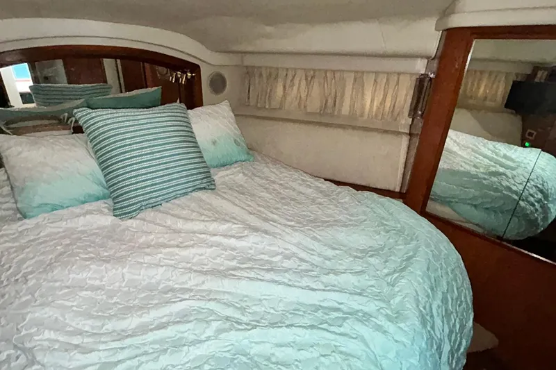 Slide: The Image of Cozy bedroom interior of 1999 Sea Ray 400 Sedan Bridge with striped pillows and mirrored accents. - 33