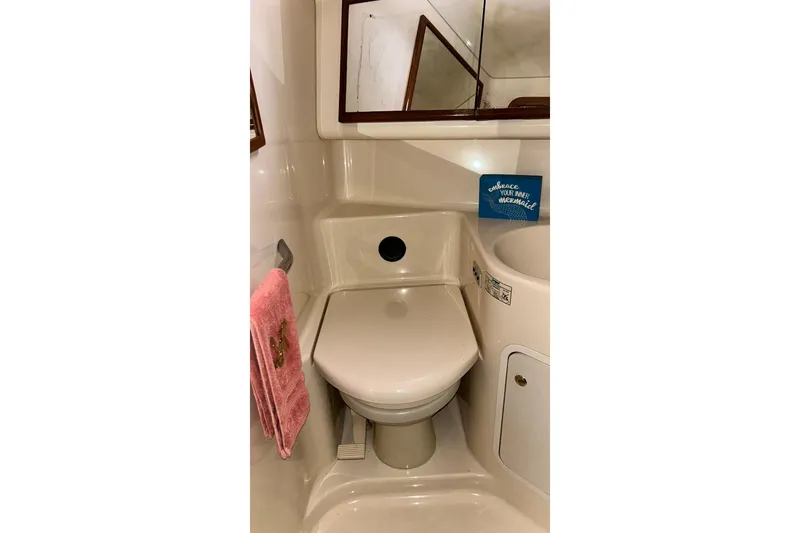 Slide: The Image of 1999 Sea Ray 400 Sedan Bridge bathroom with toilet, sink, and pink towel. - 40