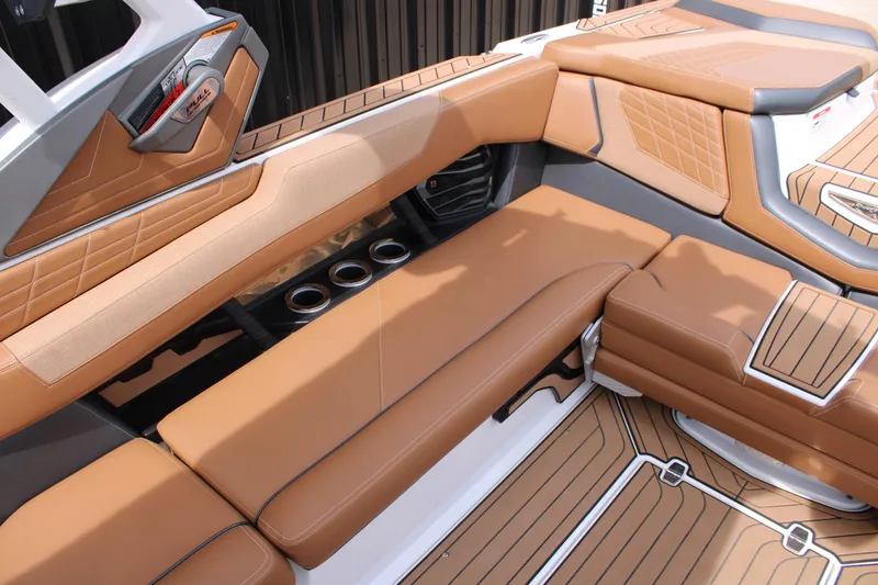 Slide: The Image of 2021 Nautique Super Air Nautique G25 interior with tan leather seating and cup holders. - 13