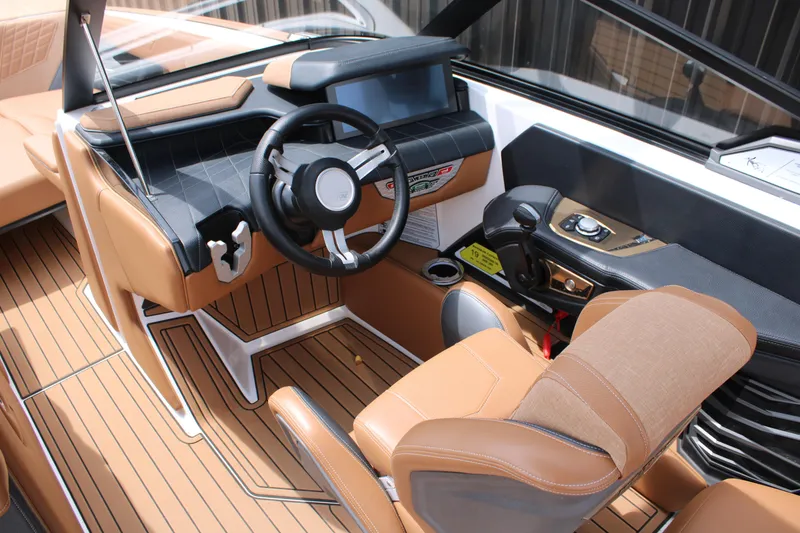 Slide: The Image of 2021 Nautique Super Air Nautique G25 boat interior with tan upholstery and modern dashboard. - 14