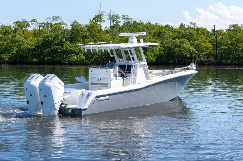 Slide: The Image of 2025 Invincible 33 Open Fisherman boat cruising on calm water near lush greenery. - 2
