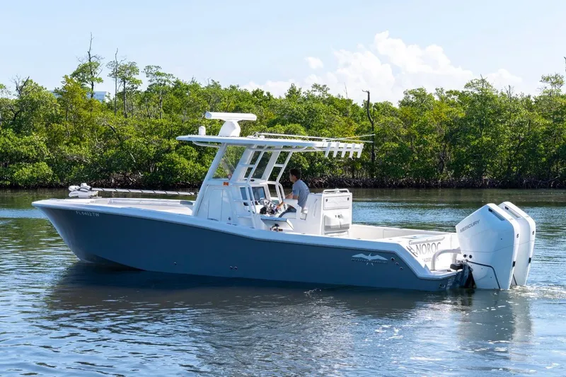 Slide: The Image of 2025 Invincible 33 Open Fisherman boat cruising on calm water near lush greenery. - 4