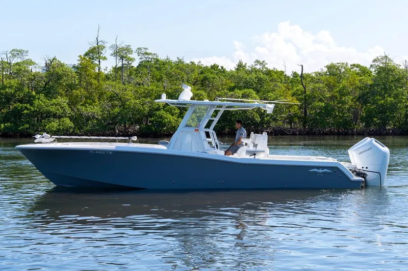 Slide: The Image of 2025 Invincible 33 Open Fisherman boat on calm water, surrounded by lush greenery. - 5