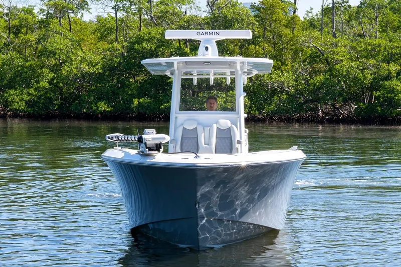 Slide: The Image of 2025 Invincible 33 Open Fisherman boat on calm water, surrounded by lush greenery. - 6