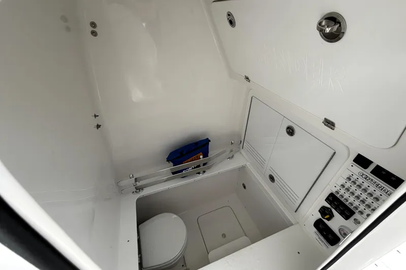 Slide: The Image of Interior of 2026 Contender 32 ST boat, featuring a compact marine toilet and control panel. - 26