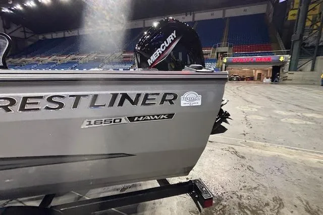 Slide: The Image of 2026 Crestliner 1650 Hawk boat with Mercury engine in indoor arena setting. - 3