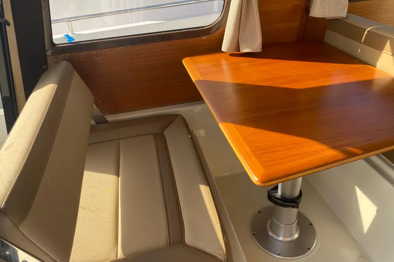 Slide: The Image of Interior of 2020 Ranger Tugs R-23 with wooden table and beige seating. - 1
