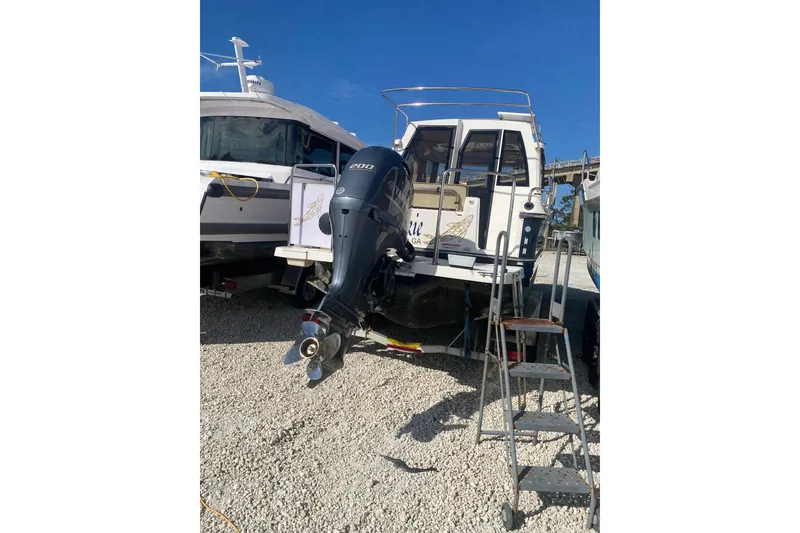 Slide: The Image of 2020 Ranger Tugs R-23 boat with outboard motor on gravel lot. - 10