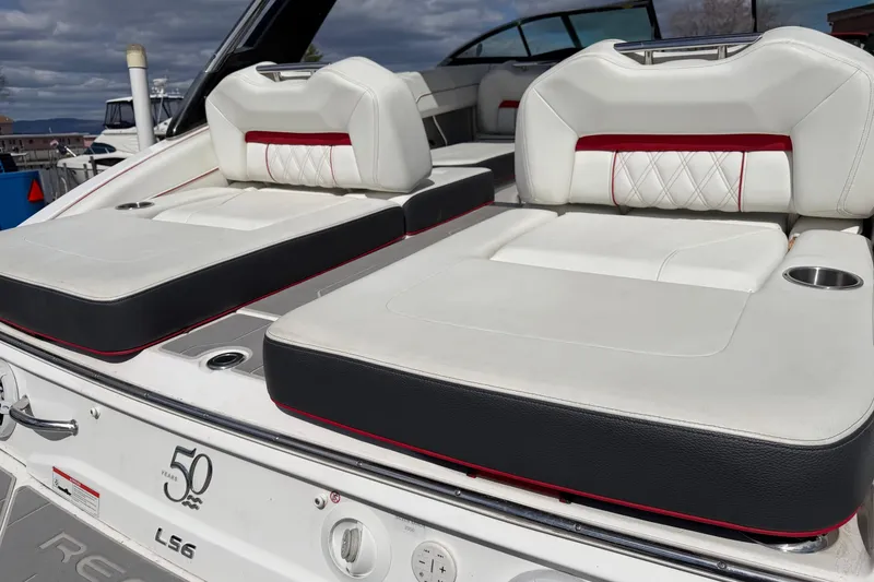 Slide: The Image of 2021 Regal LS6 boat with luxurious white and black seating, docked under cloudy skies. - 17