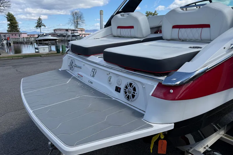 Slide: The Image of 2021 Regal LS6 boat with spacious rear seating and swim platform at a marina. - 21