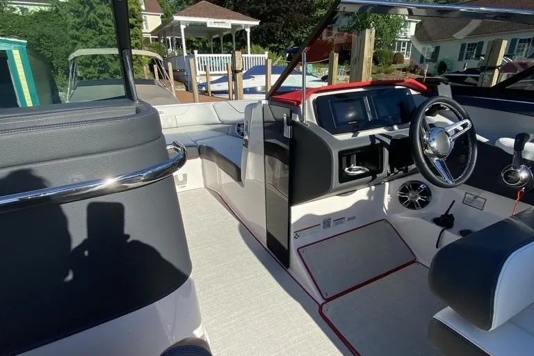Slide: The Image of 2021 Regal LS6 boat interior with modern dashboard and steering wheel, docked near waterfront homes. - 8