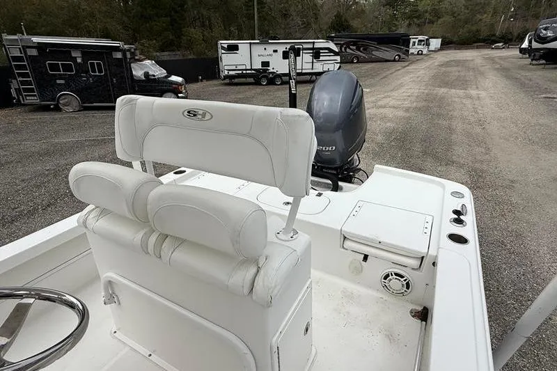 Slide: The Image of 2016 Sea Hunt BX 22 BR boat with white seating and outboard motor in a parking area. - 15