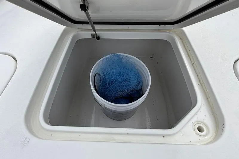 Slide: The Image of Open storage compartment on 2016 Sea Hunt BX 22 BR boat with bucket and net. - 31