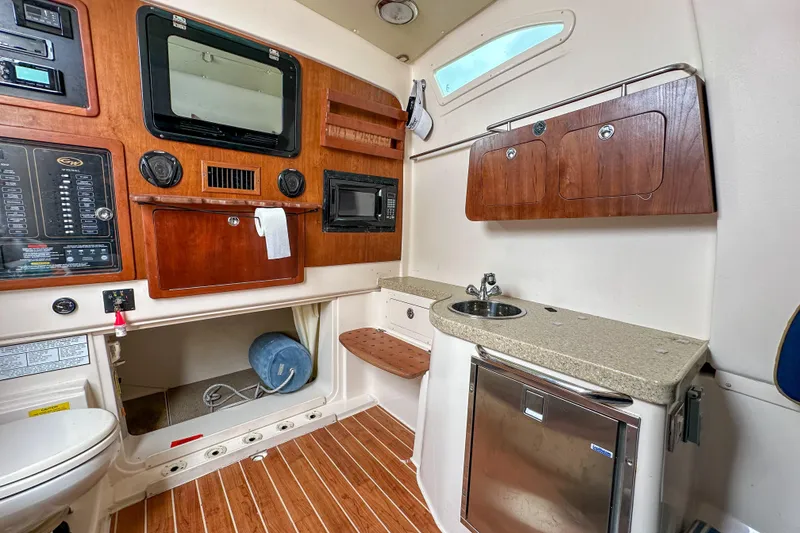 Slide: The Image of 2011 Grady-White Canyon 366 cabin interior with kitchenette, sink, and wooden cabinetry. - 51