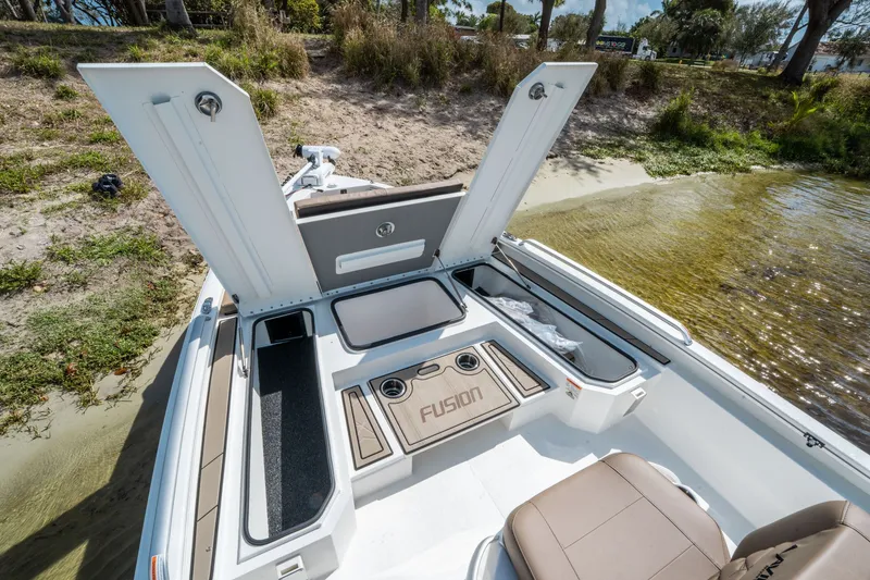 Slide: The Image of Avid 23 Fusion 2026 boat with open storage compartments by the shore. - 16