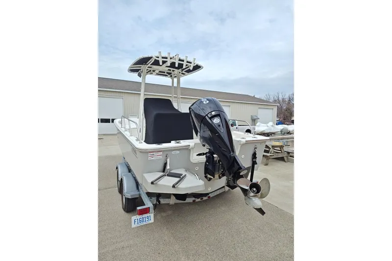 Slide: The Image of 2025 Boston Whaler 190 Montauk boat with outboard motor on trailer, parked outdoors. - 4