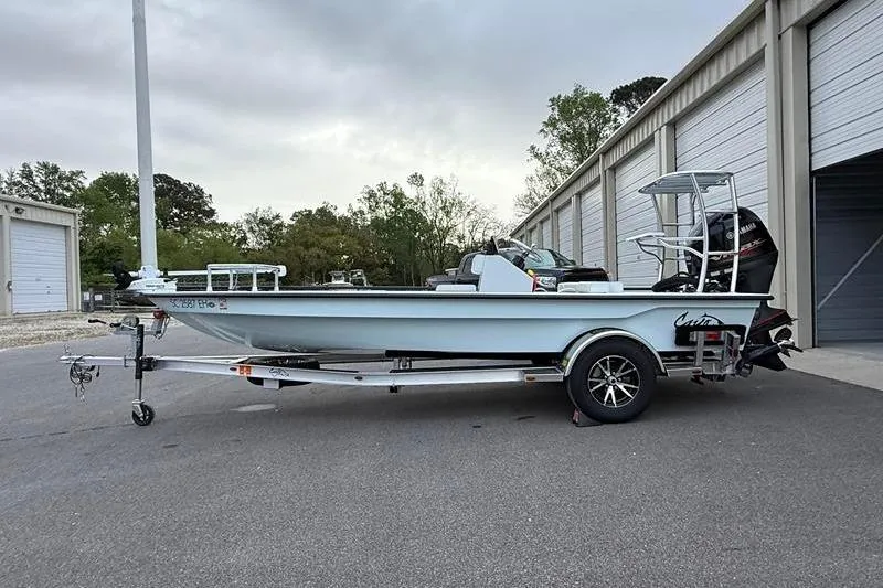 The Image of 2025 Cayo Boatworks 180 on trailer, parked near storage units, overcast sky. - 1