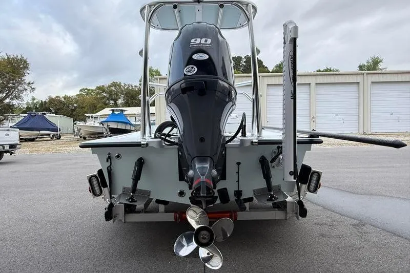 Slide: The Image of 2025 Cayo Boatworks 180 with 90 HP outboard motor, parked near storage units. - 3