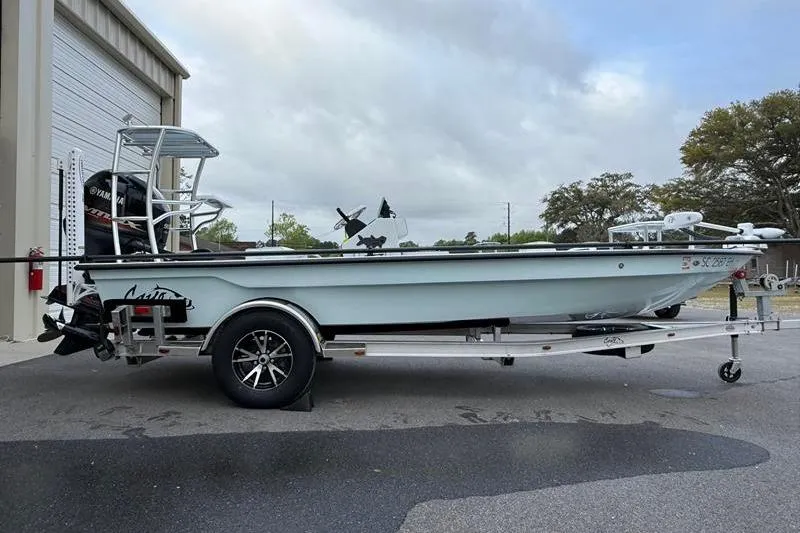 Slide: The Image of 2025 Cayo Boatworks 180 on trailer, parked outside a garage under cloudy skies. - 5