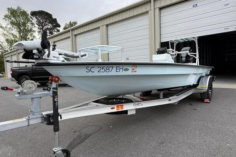 Slide: The Image of 2025 Cayo Boatworks 180 on trailer, parked outside storage units. - 7