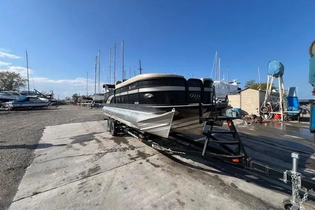 Slide: The Image of 2020 Manitou Oasis 250 pontoon boat on trailer in marina setting. - 15