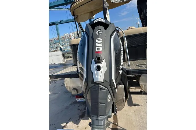 Slide: The Image of 2020 Manitou Oasis 250 with Evinrude outboard motor at a marina dock. - 2