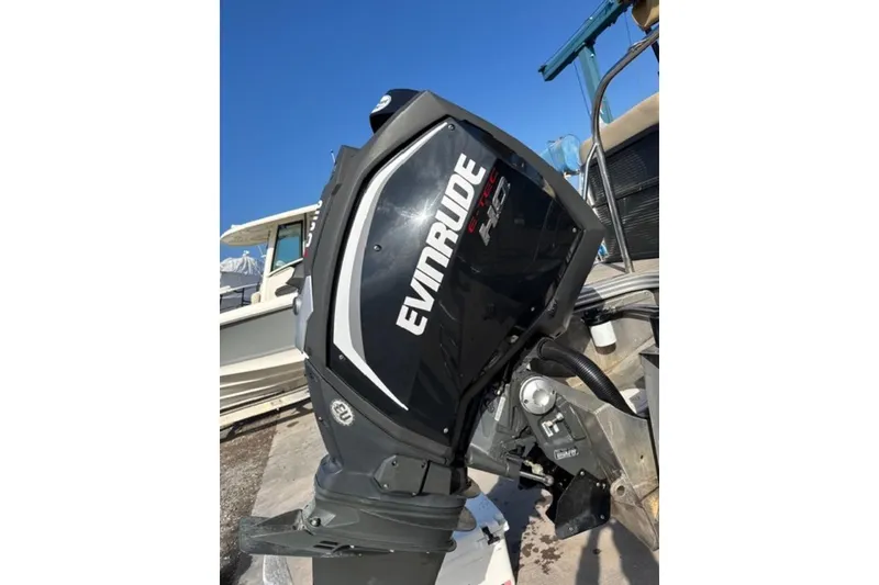 Slide: The Image of Evinrude outboard motor on 2020 Manitou Oasis 250 boat, clear blue sky background. - 3
