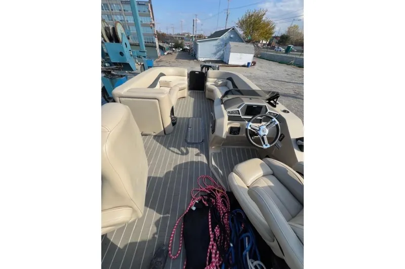 Slide: The Image of 2020 Manitou Oasis 250 pontoon boat interior with beige seating and steering console. - 8